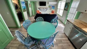 A dining area with a teal table and chairs, a black sofa, and a hammock. - Plymouth MA White Horse Beach Moana (Plymouth)