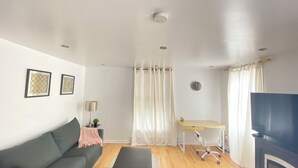 Ein Wohnzimmer mit Sofa, Schreibtisch, Fernseher und Kamin.