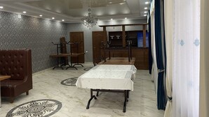 Un comedor con una mesa dispuesta para cuatro personas, una silla de cuero marrón y una araña.