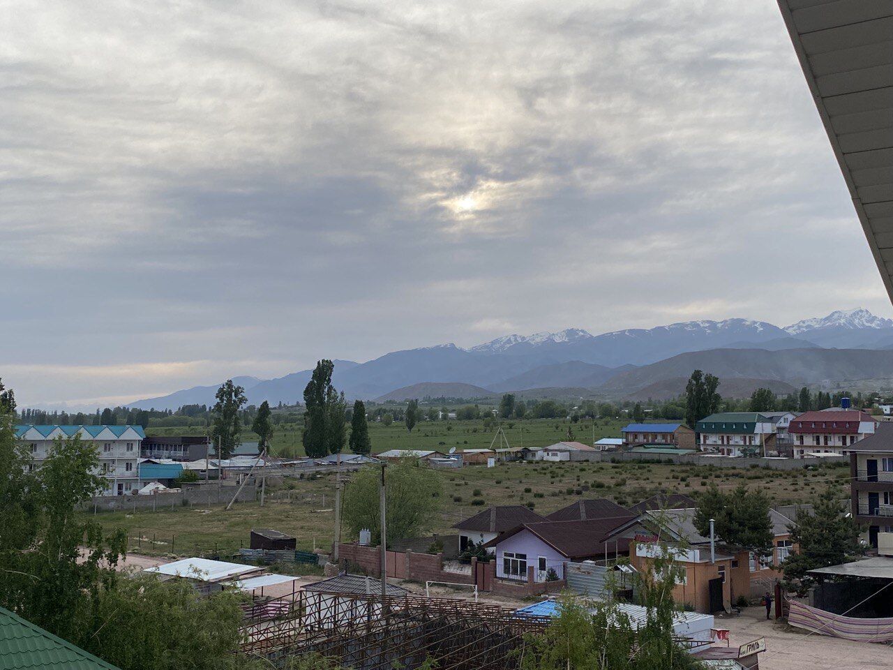 A rural landscape with houses, a construction site, and mountains in the background.