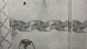 Ein Badezimmer mit Toilette, Duschbereich und einer Haltestange.