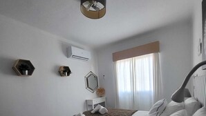 Een hotelkamer met een bed, een bedlampje, een raam met gordijnen en een wandairconditioner.
