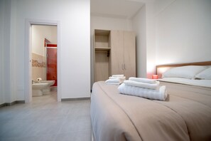 A modern hotel room with a bed, a wardrobe, and a bathroom visible through an open door. - Rocciola Home (Salerno)