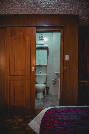 Eine Holztür zu einem Badezimmer mit Toilette, Waschbecken und Handtuchhalter.