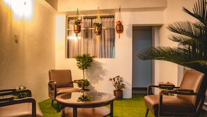 A cozy living room with a round coffee table, two brown leather chairs, a glass-top table, and hanging planters. - HOTEL EL MORLACO  (Cuenca)
