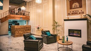 A hotel lobby with leather sofas, a fireplace, a staircase, and a sign for Hotel El Morlaco. - HOTEL EL MORLACO  (Cuenca)