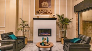 A hotel lobby with two leather sofas, a fireplace, and a framed sign above it. - HOTEL EL MORLACO  (Cuenca)