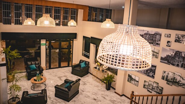 A spacious lobby with multiple seating areas, a large chandelier, and a wall adorned with black and white photographs. - HOTEL EL MORLACO  (Cuenca)