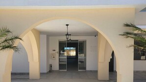 A building with a covered courtyard, arched columns, and a hanging light fixture. - Chabella - Charm Beach Lofts & Apartments - Centeanes (Carvoeiro)