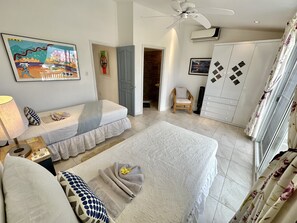 Une chambre à coucher avec un lit, une chaise, une armoire et un ventilateur de plafond.