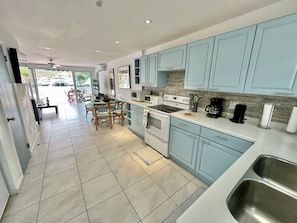 A modern kitchen with light blue cabinets, a white countertop, and stainless steel sinks.