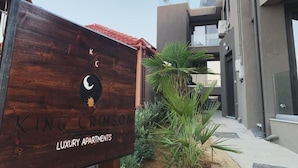Een houten bordje met 'King Crimson Luxury Apartments' en een logo in de vorm van een maan.
