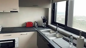 Een moderne keuken met een ingebouwde oven, een koffiezetapparaat, een broodrooster en een groot raam met uitzicht op de stad.
