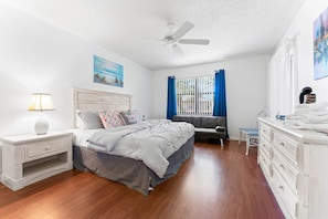 A bedroom with a bed, nightstand, dresser, and a ceiling fan.