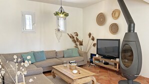 Een woonkamer met een bank, salontafel, televisie en een houtkachel.