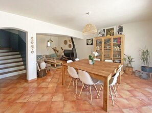 Cozy living room with a dining table and six chairs, a TV, and a bookshelf.