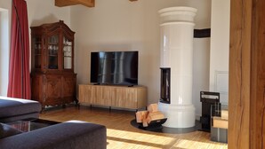 A spacious living room with wooden beams, a large flat-screen TV, a wooden cabinet, and a fireplace. - "storchenhuus", Wunderschönes Fachwerkhaus , Garten , 200 m vom Bodden (Wiek)