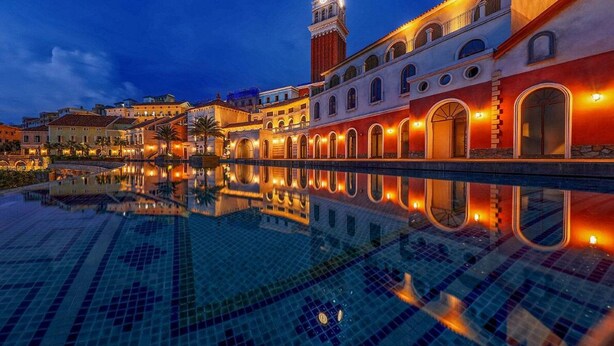 Un hôtel doté d’une piscine, d’une tour horloge et d’une façade bien éclairée.