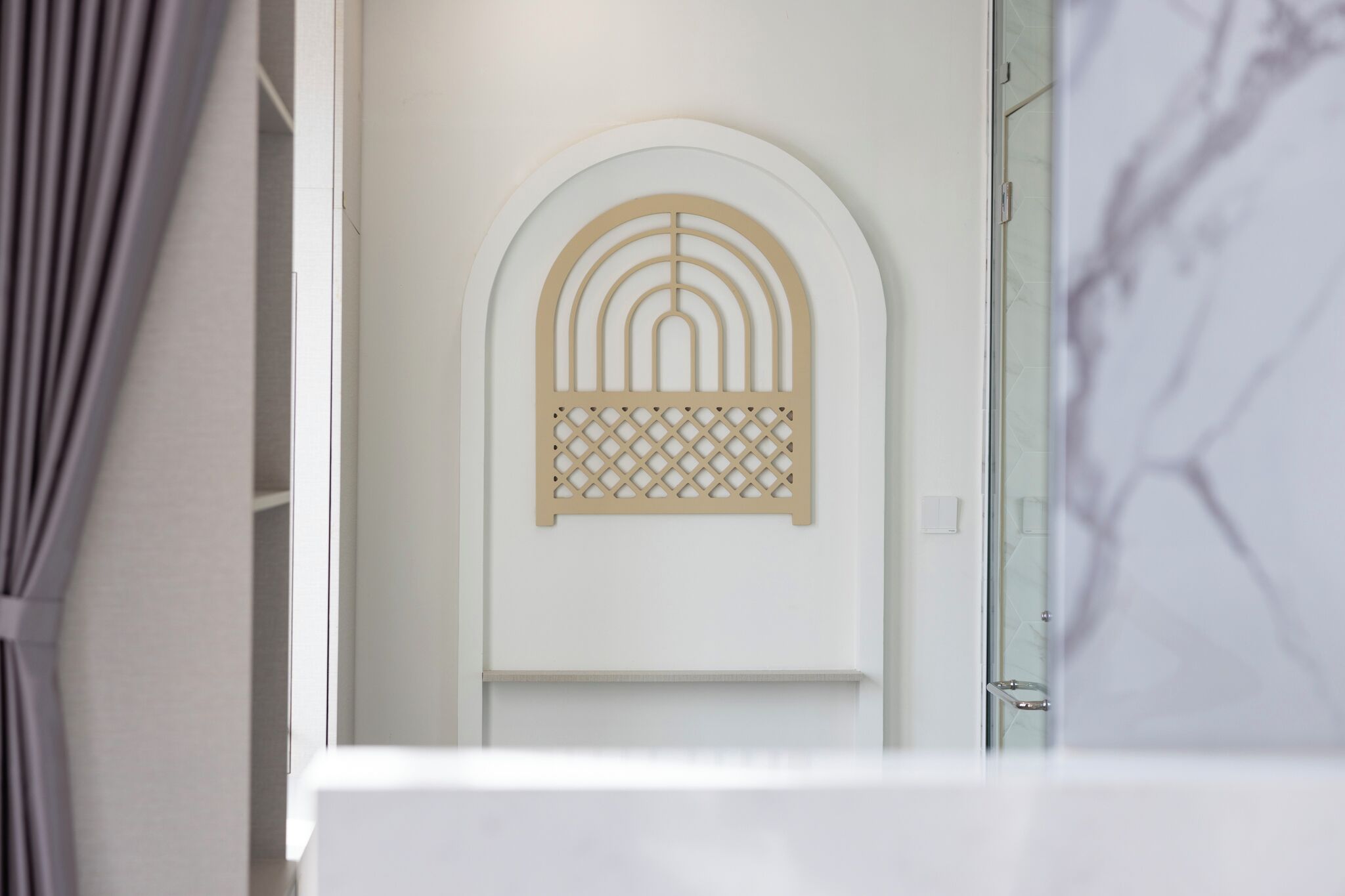 A modern bathroom with a minimalist design, featuring a white sink and a decorative wall panel with geometric patterns.