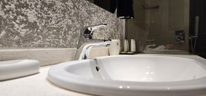 Un bagno con un lavandino bianco, un rubinetto moderno e una parete strutturata.