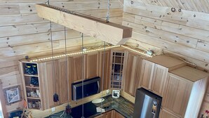 A modern kitchen with wooden cabinetry, a long wooden bar counter, and a stainless steel refrigerator.