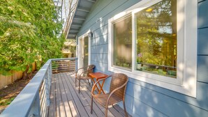 A wooden deck with wicker chairs and a table, overlooking a garden with trees. - 13 Mi to Dtwn Seattle! 'The Nest' Apt w/ Balcony (Bellevue)