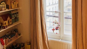 A room with a window, a radiator, and shelves with toys and decorations.
