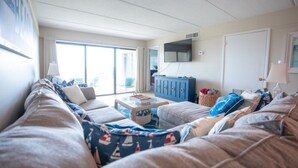 Een woonkamer met een bank, een televisie, een kast en een raam.