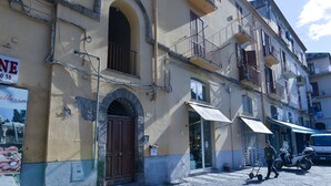 A building with a large arched entrance, a signboard, and a parked scooter. - Natalia House center of Sorrento (Sorrento)