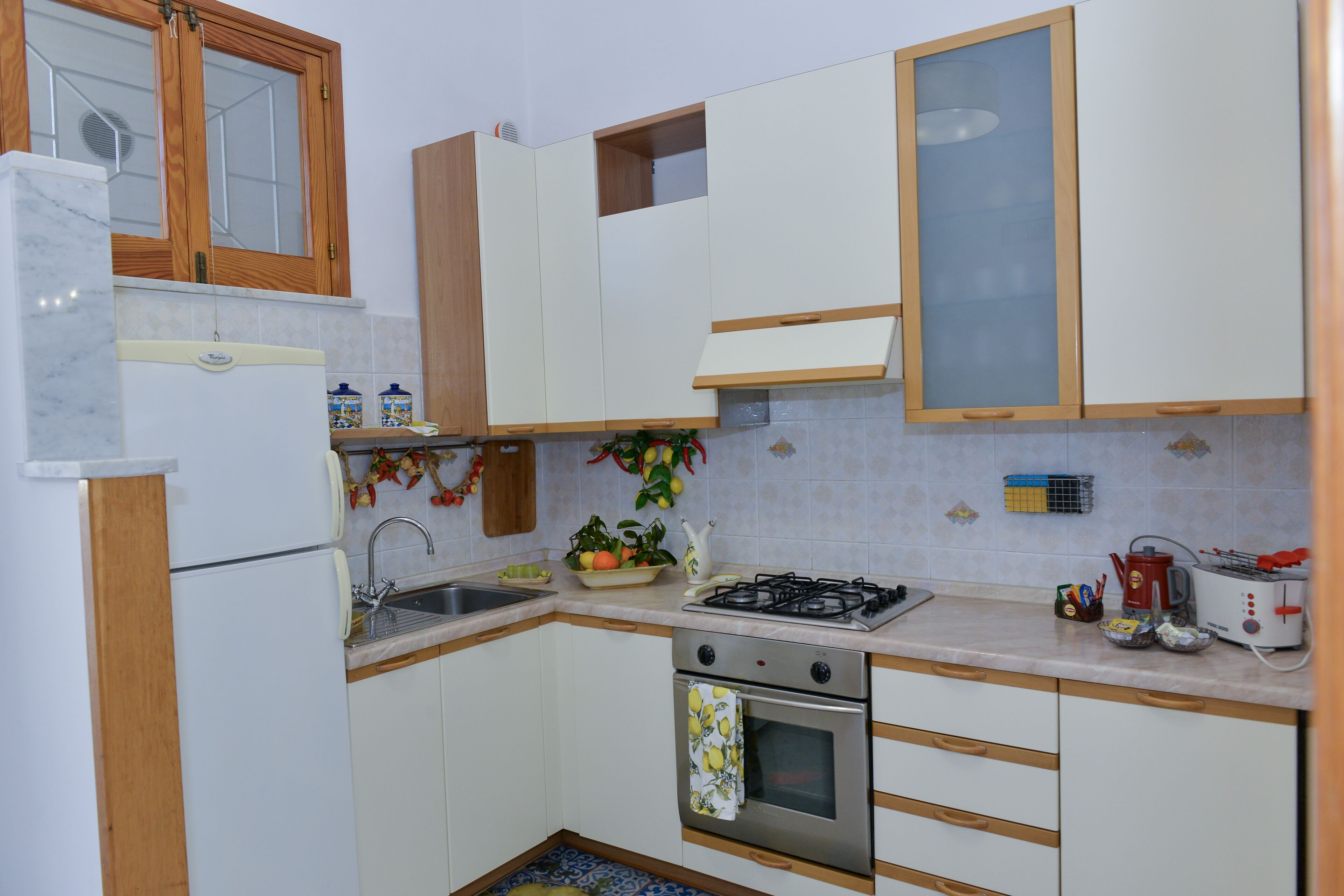 A compact kitchen with a refrigerator, sink, stove, oven, and cabinets.
