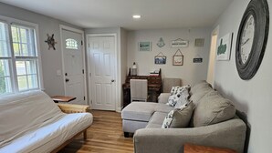A bedroom with a bed, a gray sofa, and a wooden coffee table. - Newly Renovated Mid-Cape Home with Pond and Waterfront Access (Dennis)