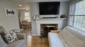 A living room with a fireplace, a television, and a sofa. - Newly Renovated Mid-Cape Home with Pond and Waterfront Access (Dennis)