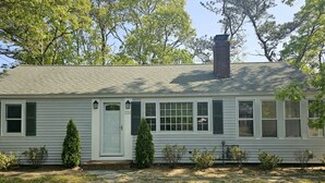 A single-story house with a gabled roof, a chimney, and a front door with a number "222". - Newly Renovated Mid-Cape Home with Pond and Waterfront Access (Dennis)
