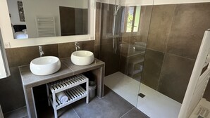 Een moderne badkamer met twee wastafels, een grote spiegel en een douchecabine van glas.