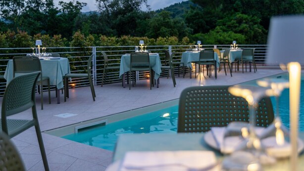 Un espace repas aménagé au bord de la piscine, avec des tables et des chaises, une piscine et une rambarde.