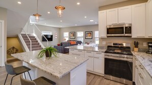 A modern kitchen with a central island, stainless steel appliances, and a staircase leading to a living area. - Spacious Minneapolis Vacation Rental w/ Game Room! (Minneapolis)