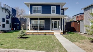 A two-story house with a covered porch and a small lawn. - Spacious Minneapolis Vacation Rental w/ Game Room! (Minneapolis)