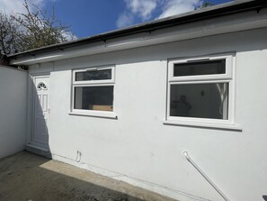 A white building with two windows and a door. - Immaculate 1-bed Studio in London (London)