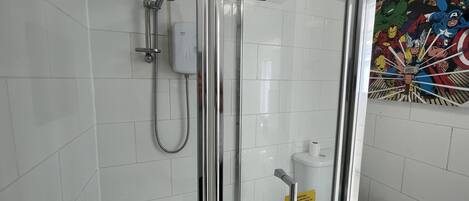 A bathroom with a shower, toilet, and a wall with a superhero-themed mural.