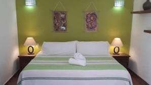 Una cama con un edredón verde y blanco a rayas, dos lámparas de noche y dos luces fijadas a la pared.
