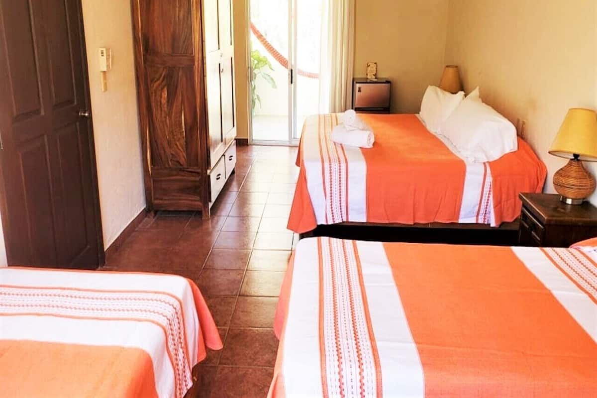 A hotel room with two beds, a small table with a lamp, and a sliding door leading to a balcony.