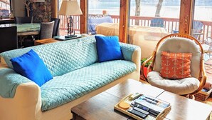 Un salon confortable avec une grande fenêtre, un canapé, un fauteuil et une table basse.