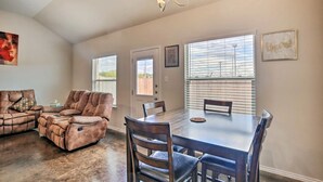 A spacious living room with a brown leather sofa, a dining table with chairs, and a chandelier. - Home away from home (Seguin)