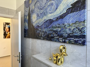 A bathroom with a large painting of a night sky and a golden sculpture on the counter.