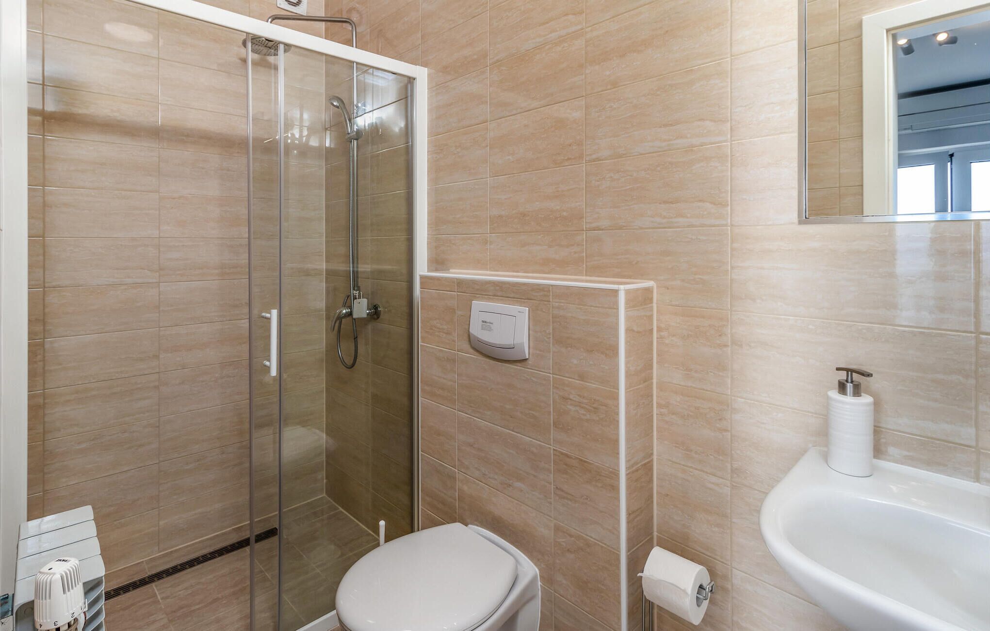 Een badkamer met een douchecabine van glas, een toilet en een wastafel.