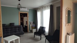 A spacious living room with a sofa, a chair, a small table, and a decorative rug. - Maison a 2 pas des Volcans (Lanobre)