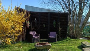 A garden with a wooden fence, outdoor furniture, and a stone bench. - Maison a 2 pas des Volcans (Lanobre)