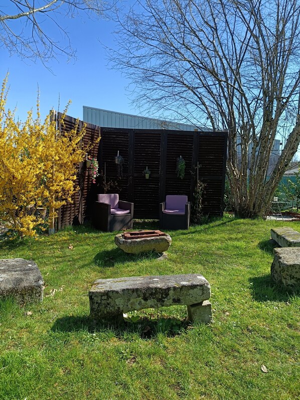 A garden with a wooden fence, outdoor furniture, and a stone bench.
