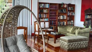 Una sala de estar con un sillón colgante, un sofá, una mesita de centro y estanterías.