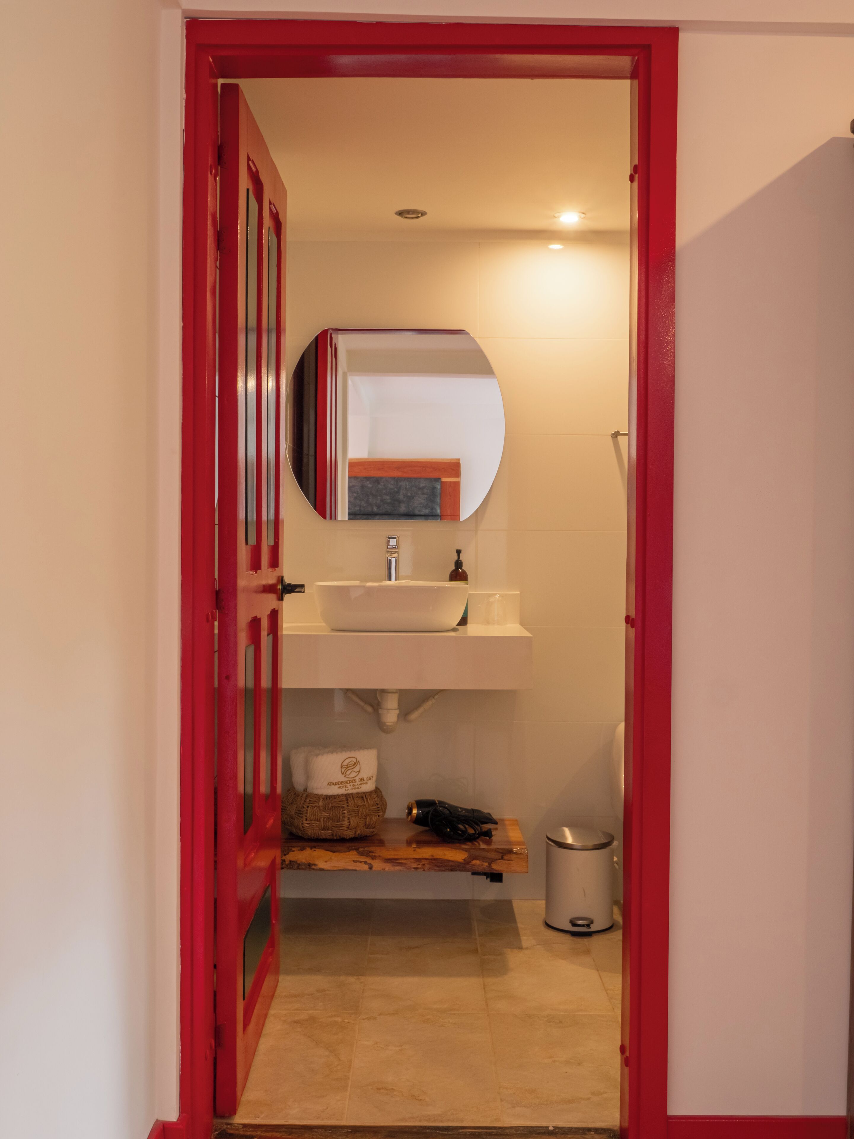 A bathroom with a white sink, a mirror, and a red door.